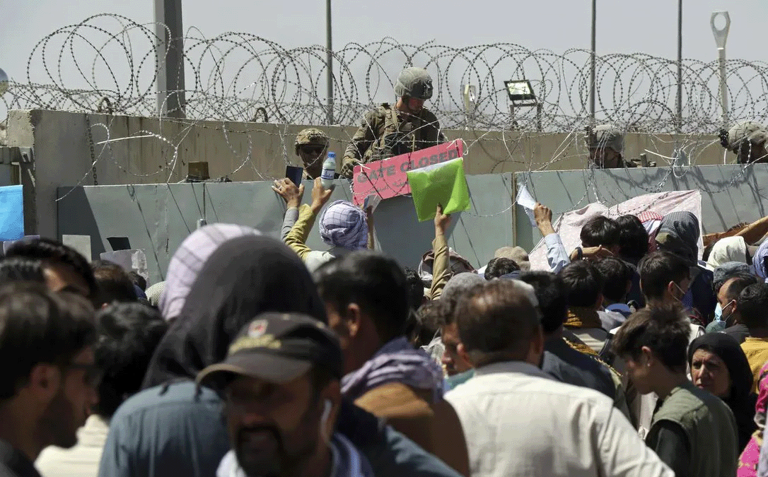 A U.S. soldier holds a sign indicating a gate is closed as hundreds of people gather — some holding documents — near an evacuation control checkpoint on the perimeter of the airport in Kabul on Aug. 26. “The termination of evacuation flights cannot end Canada’s obligation to Afghans,” writes Bruce Campion-Smith.